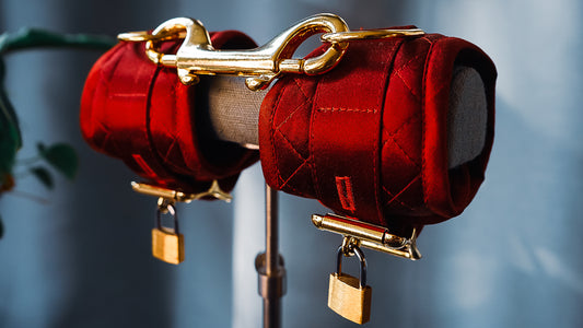 Close up of quilted satin wrist cuffs in deep red with gold hardware