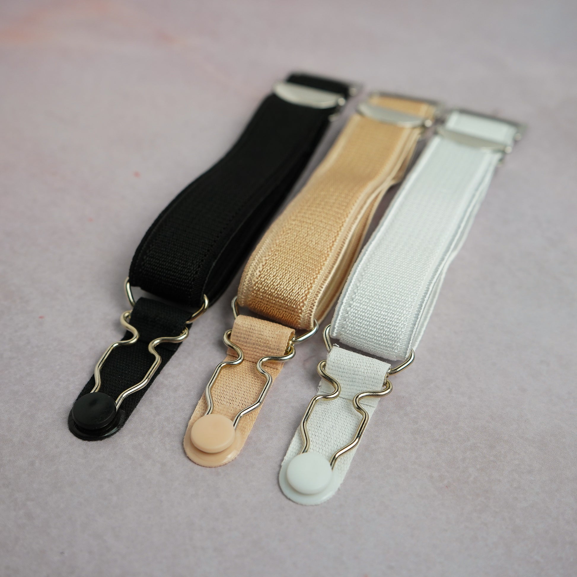 A grouping of hook on suspenders in white, black and beige.