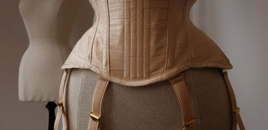 A close-up of a gold silk corset on a mannequin