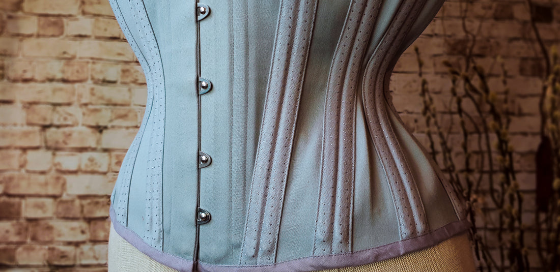 A close up of a grey mens corset with spot detailing