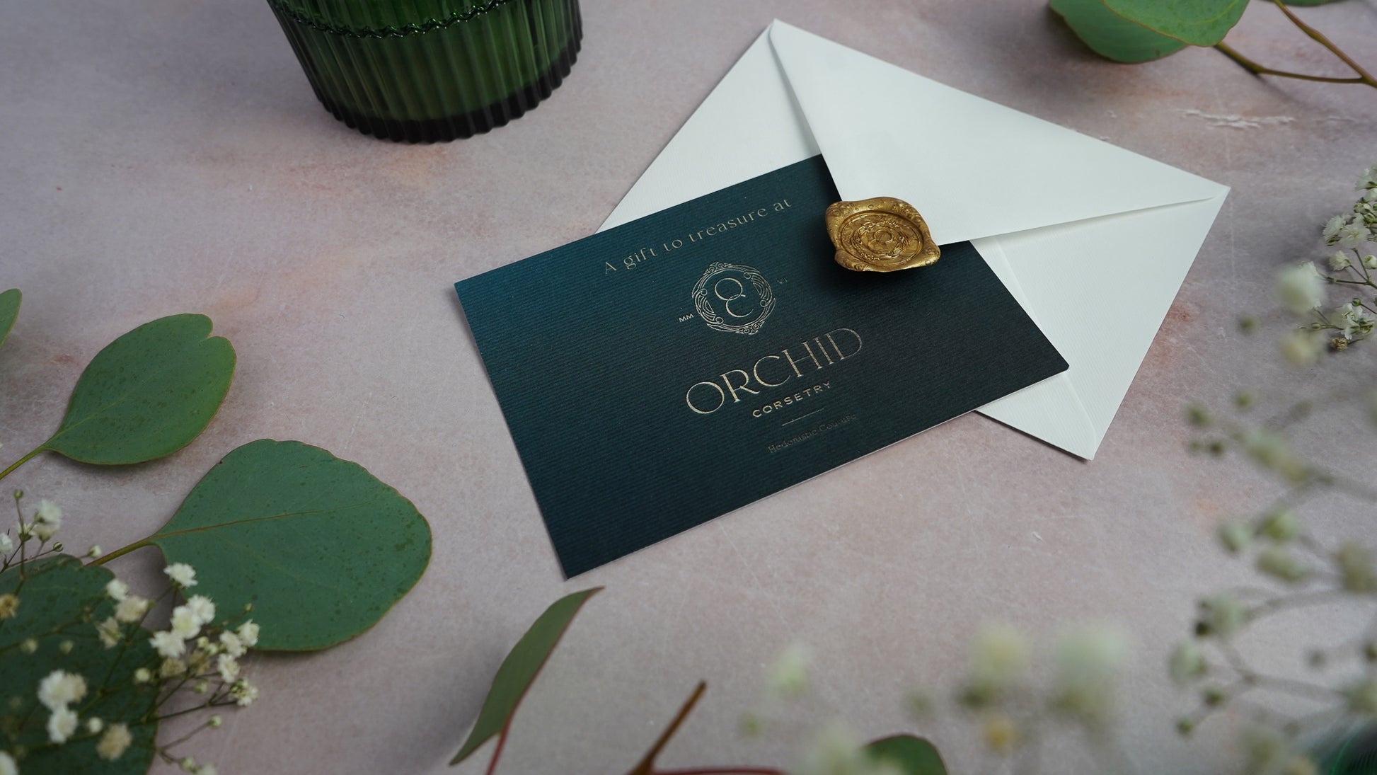 An Orchid Corsetry gift card with a gold wax sealed envelope